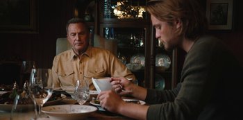 Movie still from “Yellowstone” (2018), created by John Linson – Two men sitting at a dinner table looking at a tablet computer; Medium shot, Over the shoulder angle