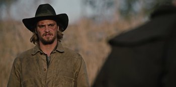Movie still from “Yellowstone” (2018), created by John Linson – A man in a cowboy hat and a brown jacket; Close Up shot, Over the shoulder angle