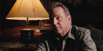 Movie still from “Yellowstone” (2018), created by John Linson – An older man sitting in front of a lamp; Close Up shot, Over the shoulder angle