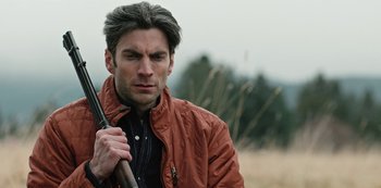 Movie still from “Yellowstone” (2018), created by John Linson – A person holding a gun; Close Up shot, Over the shoulder angle
