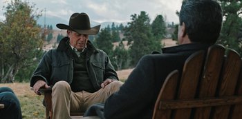 Movie still from “Yellowstone” (2018), created by John Linson – A man in a cowboy hat sitting next to another man in a cowboy hat; Medium shot, Over the shoulder angle