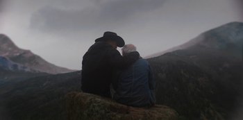 Movie still from “Yellowstone” (2018), created by John Linson – Two men sitting on a rock in the mountains; Wide shot, Over the shoulder angle