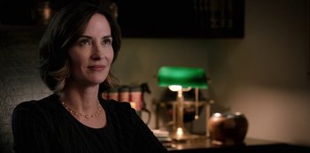 Movie still from “Yellowstone” (2018), created by John Linson – A person sitting in a room near a lamp; Close Up shot, Over the shoulder angle