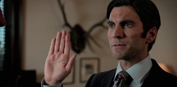 Movie still from “Yellowstone” (2018), created by John Linson – A man in a suit and tie raising his right hand; Close Up shot, Over the shoulder angle