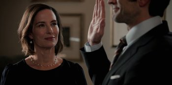 Movie still from “Yellowstone” (2018), created by John Linson – A man in a suit is being sworn in by a woman in a black dress; Close Up shot, Over the shoulder angle