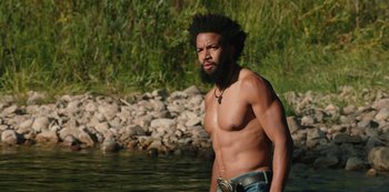 Movie still from “Yellowstone” (2018), created by John Linson – A man with a beard is standing in the water; Medium shot, Low angle