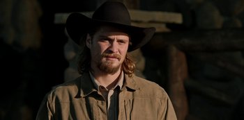 Movie still from “Yellowstone” (2018), created by John Linson – A man with a long beard wearing a cowboy hat; Close Up shot, Over the shoulder angle