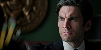 Movie still from “Yellowstone” (2018), created by John Linson – A person wearing a suit and tie; Close Up shot, Low angle