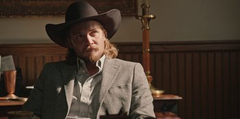 Movie still from “Yellowstone” (2018), created by John Linson – A man in a cowboy hat and a suit; Close Up shot, Over the shoulder angle