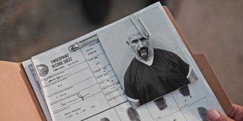 Movie still from “Yellowstone” (2018), created by John Linson – A picture of a man with a shaved head and a pair of scissors stuck to his head; Extreme Close Up shot, Overhead angle