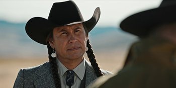 Movie still from “Yellowstone” (2018), created by John Linson – A man in a cowboy hat and a tie; Close Up shot, Over the shoulder angle