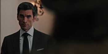 Movie still from “Yellowstone” (2018), created by John Linson – A person wearing a suit and tie; Close Up shot, Over the shoulder angle