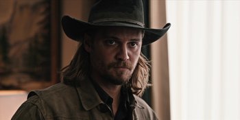 Movie still from “Yellowstone” (2018), created by John Linson – A person wearing a hat with long hair; Close Up shot, Over the shoulder angle