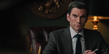 Movie still from “Yellowstone” (2018), created by John Linson – A man in a suit sitting in a chair; Close Up shot, Low angle