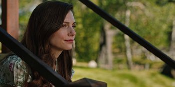 Movie still from “Yellowstone” (2018), created by John Linson – A beautiful woman sitting on a bench in a park; Close Up shot, Over the shoulder angle