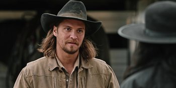 Movie still from “Yellowstone” (2018), created by John Linson – A man with long hair wearing a cowboy hat; Close Up shot, Over the shoulder angle