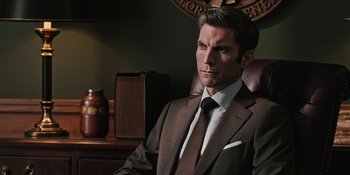 Movie still from “Yellowstone” (2018), created by John Linson – A man in a suit sitting in a chair; Close Up shot, Over the shoulder angle