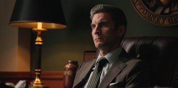 Movie still from “Yellowstone” (2018), created by John Linson – A person wearing a suit and tie; Close Up shot, Low angle