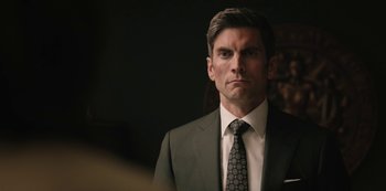 Movie still from “Yellowstone” (2018), created by John Linson – A person wearing a suit and tie; Close Up shot, Over the shoulder angle