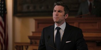 Movie still from “Yellowstone” (2018), created by John Linson – A man in a black suit and a white tie; Close Up shot, Over the shoulder angle