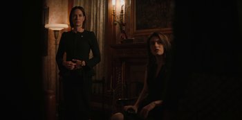Movie still from “Yellowstone” (2018), created by John Linson – Two women are sitting in a dark living room; Medium shot, Over the shoulder angle