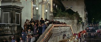 Movie still from “Yesterday, Today and Tomorrow” (1963), directed by Vittorio De Sica – A group of people sitting on steps near a building; Extreme Wide shot, High angle
