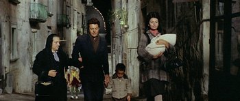 Movie still from “Yesterday, Today and Tomorrow” (1963), directed by Vittorio De Sica – A man and a woman walking down a street with a child; Medium shot, High angle
