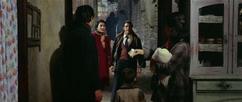 Movie still from “Yesterday, Today and Tomorrow” (1963), directed by Vittorio De Sica – A group of people standing around in an alleyway; Medium shot, Over the shoulder angle