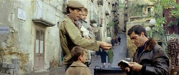 Movie still from “Yesterday, Today and Tomorrow” (1963), directed by Vittorio De Sica – A man holding a child in his arms while walking down a street; Medium shot, High angle