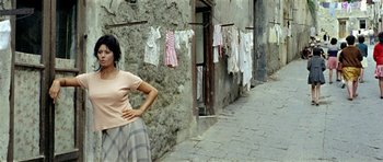 Movie still from “Yesterday, Today and Tomorrow” (1963), directed by Vittorio De Sica – A woman standing in front of a stone wall with clothes hanging on a line; Medium shot, Low angle
