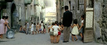 Movie still from “Yesterday, Today and Tomorrow” (1963), directed by Vittorio De Sica – A group of people walking down a street with buildings in the background; Wide shot, High angle