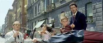 Movie still from “Yesterday, Today and Tomorrow” (1963), directed by Vittorio De Sica – A man and two children riding a motorcycle; Medium shot, Over the shoulder angle
