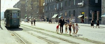 Movie still from “Yesterday, Today and Tomorrow” (1963), directed by Vittorio De Sica – A man walking down a street with a group of children; Extreme Wide shot, High angle