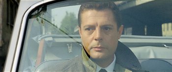 Movie still from “Yesterday, Today and Tomorrow” (1963), directed by Vittorio De Sica – A person wearing a suit and tie in a car; Close Up shot, Over the shoulder angle