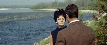 Movie still from “Yesterday, Today and Tomorrow” (1963), directed by Vittorio De Sica – A man and a woman standing next to a body of water; Medium shot, Over the shoulder angle