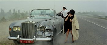 Movie still from “Yesterday, Today and Tomorrow” (1963), directed by Vittorio De Sica – A woman in a black dress is walking past a car; Wide shot, High angle