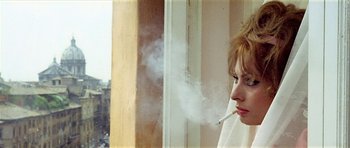 Movie still from “Yesterday, Today and Tomorrow” (1963), directed by Vittorio De Sica – A woman smoking a cigarette in front of a window; Close Up shot, Low angle