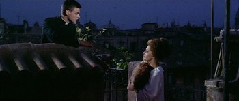 Movie still from “Yesterday, Today and Tomorrow” (1963), directed by Vittorio De Sica – A man and a woman standing next to each other on top of a building; Medium shot, Low angle