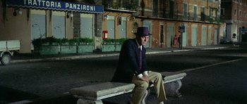 Movie still from “Yesterday, Today and Tomorrow” (1963), directed by Vittorio De Sica – A man sitting on top of a wooden bench on the street; Wide shot, High angle