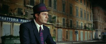 Movie still from “Yesterday, Today and Tomorrow” (1963), directed by Vittorio De Sica – A man in a suit and hat sitting in front of a building; Medium shot, Low angle