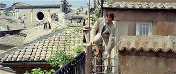 Movie still from “Yesterday, Today and Tomorrow” (1963), directed by Vittorio De Sica – A man in a tan suit climbing a fence; Wide shot, Low angle