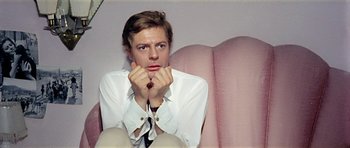 Movie still from “Yesterday, Today and Tomorrow” (1963), directed by Vittorio De Sica – A man sitting on top of a pink couch with his hands under his chin; Close Up shot, High angle