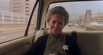 Movie still from “Yi Yi” (2000), directed by Edward Yang – An older woman sitting in the back seat of a car; Close Up shot, Low angle