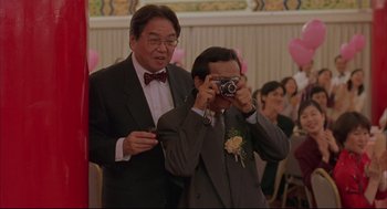 Movie still from “Yi Yi” (2000), directed by Edward Yang – Two men in suits taking a picture with a camera; Medium shot, Low angle
