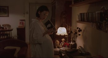 Movie still from “Yi Yi” (2000), directed by Edward Yang – A pregnant woman reading a book in a living room; Medium shot, High angle