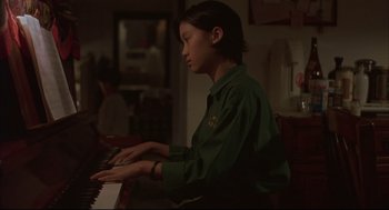 Movie still from “Yi Yi” (2000), directed by Edward Yang – A person sitting at a piano in a living room; Medium shot, High angle