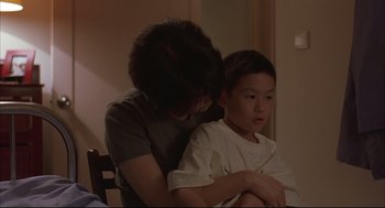 Movie still from “Yi Yi” (2000), directed by Edward Yang – A woman sitting next to a boy in a room; Medium shot, Over the shoulder angle