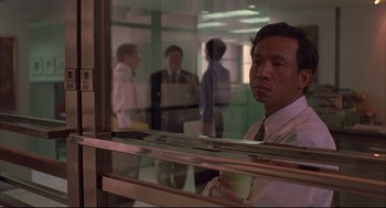 Movie still from “Yi Yi” (2000), directed by Edward Yang – A man in a suit and tie in front of a window; Medium shot, Low angle