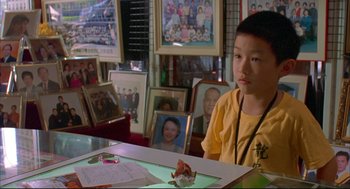 Movie still from “Yi Yi” (2000), directed by Edward Yang – A young boy sitting at a table in front of pictures; Close Up shot, High angle