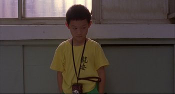 Movie still from “Yi Yi” (2000), directed by Edward Yang – A boy in a yellow shirt is holding a camera; Medium shot, High angle